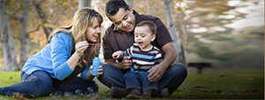 Two adults blowing bubbles with child